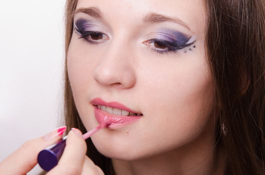 Makeup artist paints her lips a beautiful young girl in the makeup