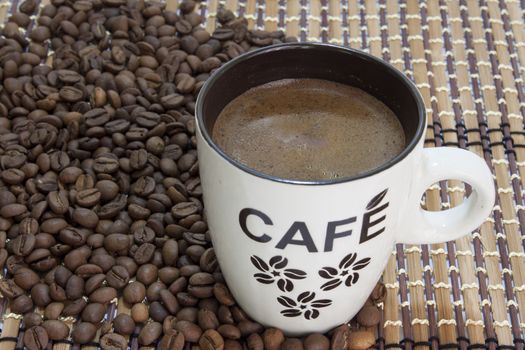 Cup of coffe on the bamboo background and coffee beans.