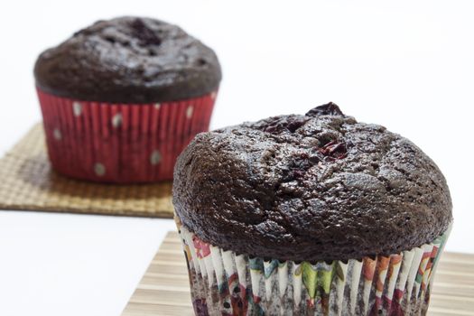Chocolate muffins on a bamboo mat and white background.