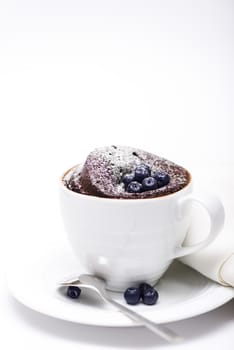 Chocolate cake in a mug on white background with spoon and napkin