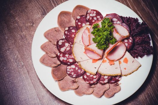 cut meat platter on white plate with greens