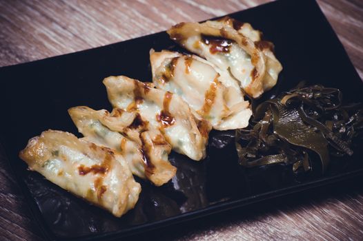 fried gyoza dumplings with sauce on black plate 