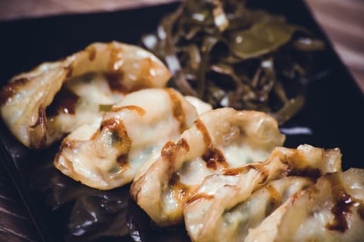 fried gyoza dumplings with sauce on black plate 