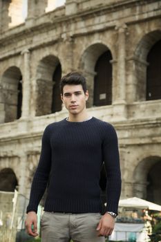 Attractive young man in Rome standing in front of the Colosseum, looking at camera