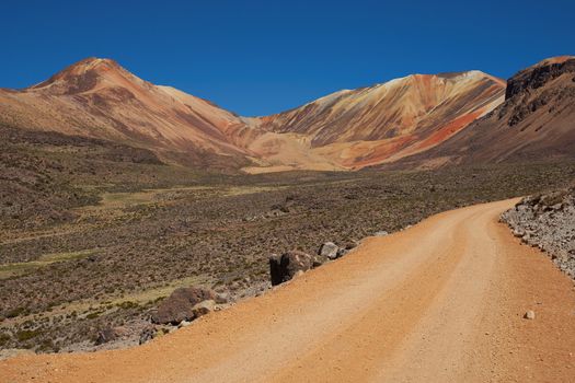 Orange coloured gravel road running through naturally coloured mountains high in the Atacama Desert of north east Chile. The altitude is in excess of 4,000 metres.