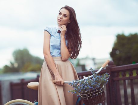 Young beautiful, elegantly dressed woman with bicycle. Beauty, fashion and lifestyle