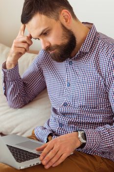 Young bearded man working on laptop at home