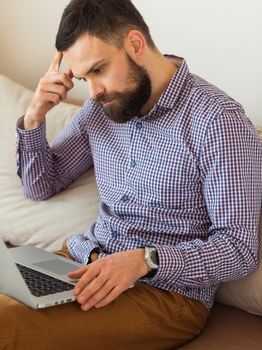 Young bearded man working on laptop at home