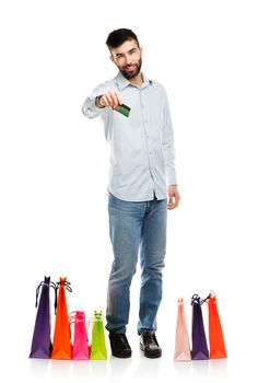 Handsome smiling man with shopping bags and holding credit card. Christmas and holidays concept