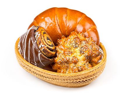 Fresh and tasty buns with with sesame and poppy seeds, bagel with jam and roll with chocolate in a basket over white background