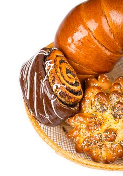 Fresh and tasty buns with with sesame and poppy seeds, bagel with jam and roll with chocolate in a basket over white background