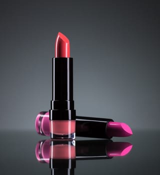 Two bright lipsticks on a black background