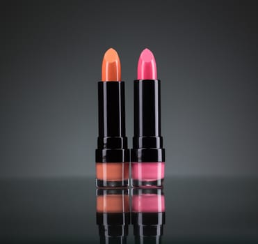 Two bright lipsticks on a black background