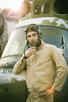 Young serious pilot posing near the helicopter