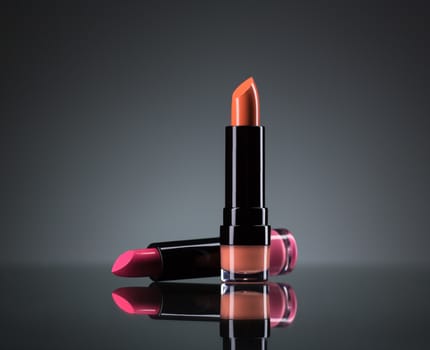 Two bright lipsticks on a black background