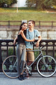 Happy couple - young smiling man and woman with bike in the park outdoor