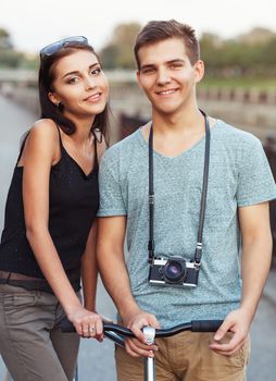 Happy couple - young smiling man and woman with bike in the park outdoor