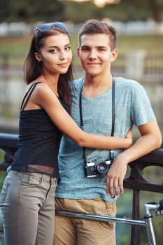 Happy couple - young smiling man and woman with bike in the park outdoor