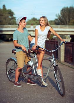 Happy couple - man and woman riding a bicycle in the city street