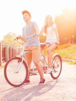 Happy couple - man and woman riding a bicycle in the city street