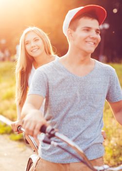 Happy couple - man and woman riding a bicycle in the city street