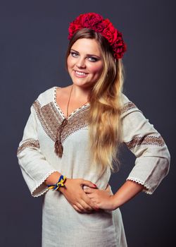 Young beautiful smiling girl in Ukrainian costume with a red wreath on her head