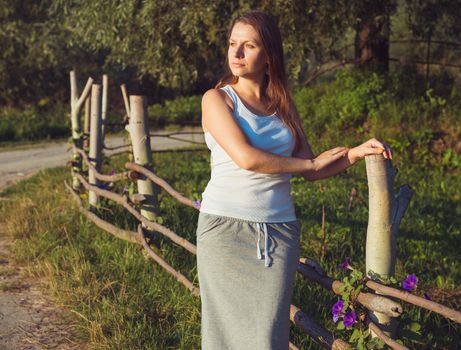 Brunette girl outdoors summer day near the fence