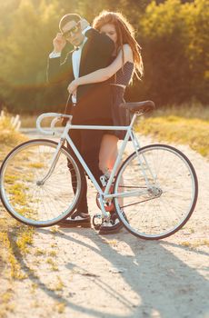 Young stylish couple - the guy with the girl and bicycle outdoors