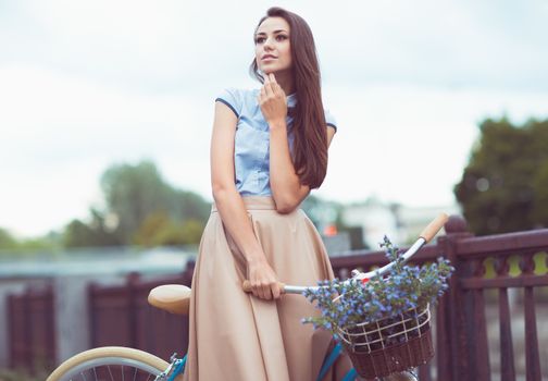 Young beautiful, elegantly dressed woman with bicycle. Beauty, fashion and lifestyle