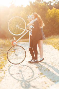 Young stylish couple - the guy with the girl and bicycle outdoors