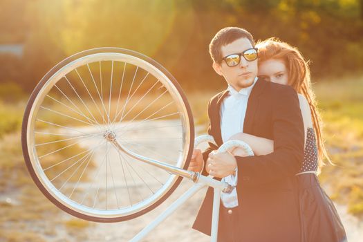 Young stylish couple - the guy with the girl and bicycle outdoors