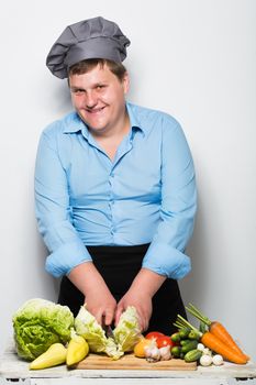 Plump cook on gray wall background