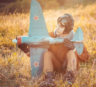 Young guy in vintage clothes pilot with an airplane model outdoors