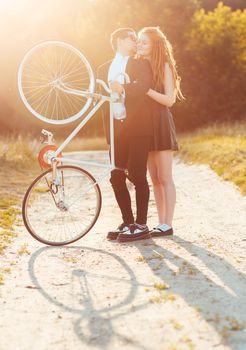 Young stylish couple - the guy with the girl and bicycle outdoors
