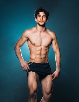 Athletic attractive man after fitness exersise on the blue background