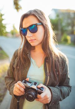 Close up lifestyle portrait of pretty young fashion brunette in sun glasses on the sun at sunset