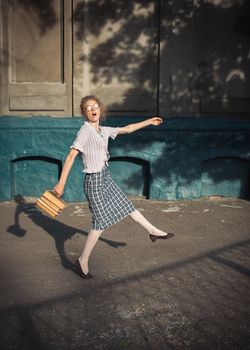 Funny girl student with books in glasses and a vintage dress outdoors