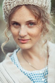 Funny attractive girl with freckles and curly hair in a vintage dress and beret outdoors