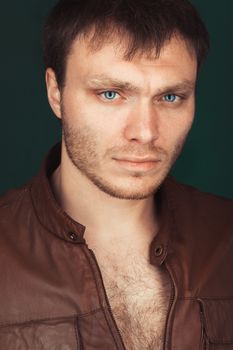 Portrait of a smart serious young man standing against dark background