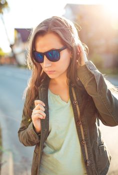 Close up lifestyle portrait of pretty young fashion brunette in sun glasses on the sun at sunset