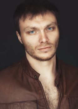 Portrait of a smart serious young man standing against dark background