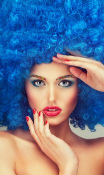 Portrait of a young beautiful girl with bright makeup, red lips in blue wig