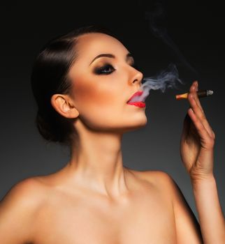 Portrait of a beautiful young woman with cigar and with a glamorous retro makeup