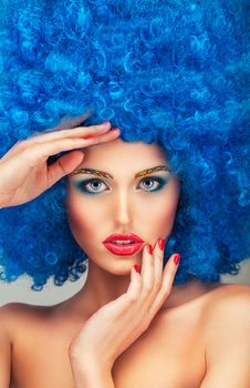 Portrait of a young beautiful girl with bright makeup, red lips in blue wig