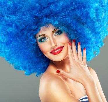 Portrait of a young beautiful girl with bright makeup, red lips in blue wig