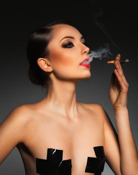 Portrait of a beautiful young woman with cigar and with a glamorous retro makeup