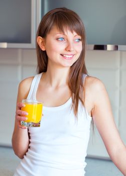 Young caucasian brunette girl with a glass of juice in the kitchen