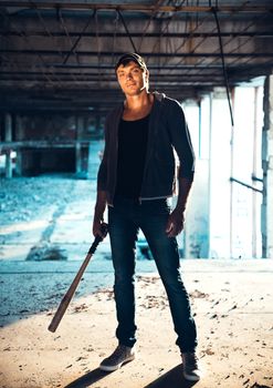 Muscular man with baseball bat on the ruins