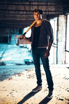 Muscular man with baseball bat on the ruins