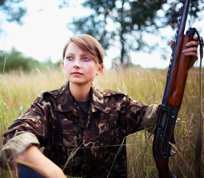 Young beautiful girl with a shotgun in an outdoor